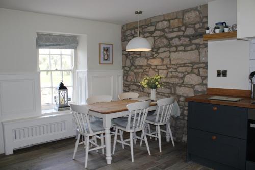 cocina con mesa, sillas y pared de piedra en Herds House Belcoo en Belcoo