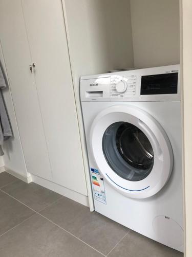a white washing machine in a kitchen next to a cabinet at Residentie Zeezicht in Eksel