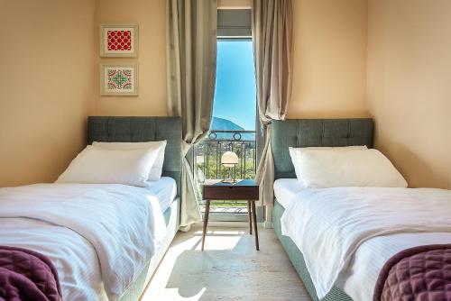 two beds in a room with a window at 2MONTENEGRO LIMETA APARTMENTS with pool in Kotor