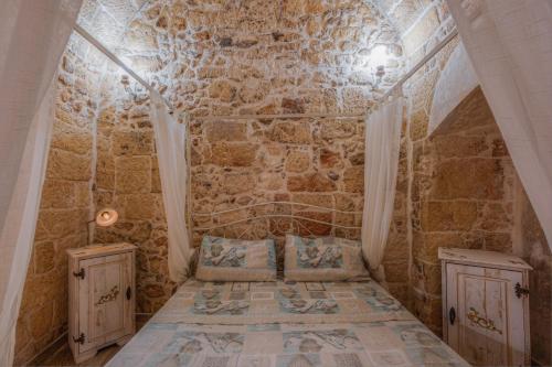 a room with a stone wall with a bed and two cabinets at Le casette di Nardò in Nardò