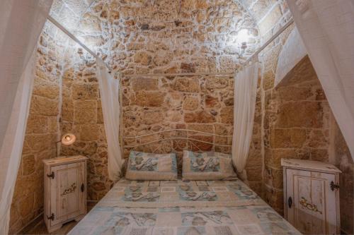 ナルドにあるLe casette di Nardòの石壁の客室で、ベッド1台、キャビネット2台が備わります。