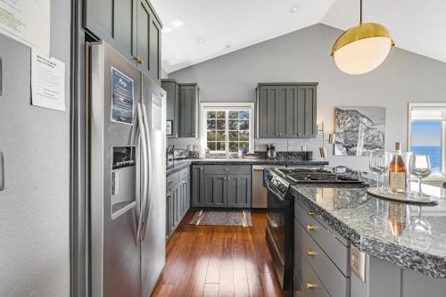 a kitchen with gray cabinets and a stainless steel refrigerator at Oceanside Oasis in Oceanside