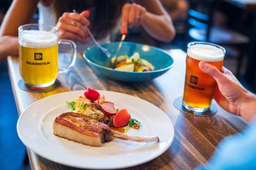 a table with a plate of food and two glasses of beer at Pivovar Falkenštejn in Krásná Lípa