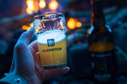 a hand holding a glass of beer next to a bottle at Pivovar Falkenštejn in Krásná Lípa