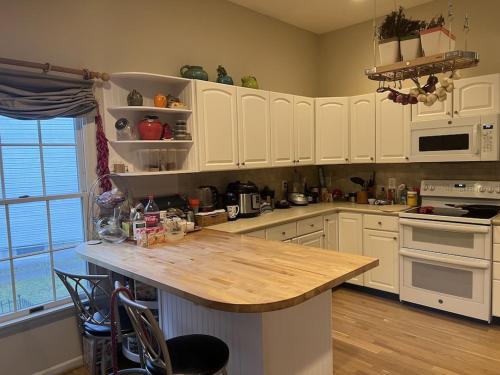 a kitchen with white cabinets and a wooden counter top at 5BRwithBand&Piano setup Private Gym Theater&Entry at Cherry Hill in Cherry Hill