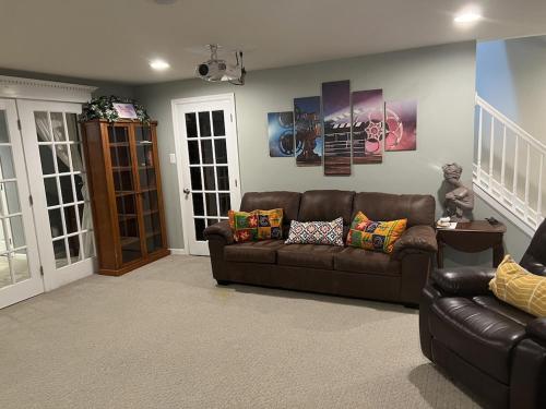 a living room with a brown leather couch at 5BRwithBand&Piano setup Private Gym Theater&Entry at Cherry Hill in Cherry Hill