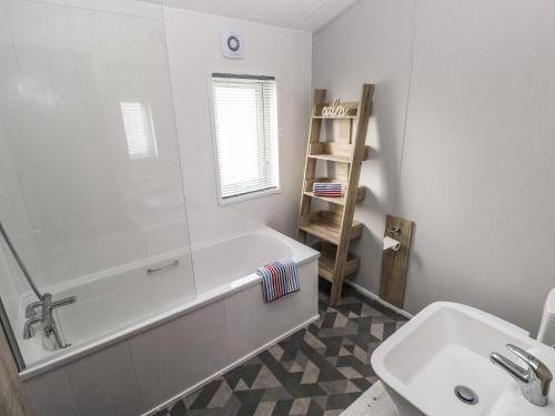 a white bathroom with a tub and a sink at 69 The Paddocks in Carmarthen