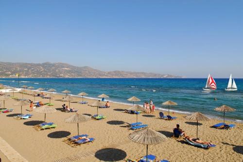 a group of people sitting on a beach with umbrellas at Eva's Studio in Heraklio
