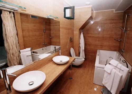 a bathroom with two sinks and a toilet and a tub at Park Hotel Sandanski in Sandanski