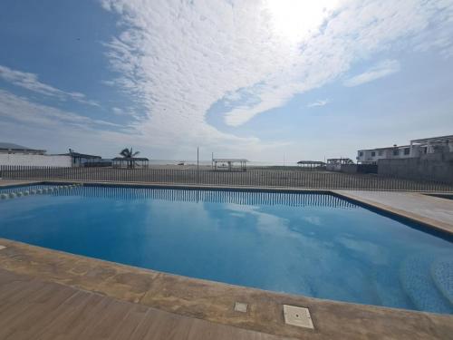 a large blue swimming pool with a cloudy sky at Ecusuites Playas Preference Penthouse Jacuzzi & Vista Mar in Playas