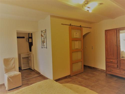 a room with a bed and a door and a chair at Chambres d'hôtes La Dorgisane in Venterol