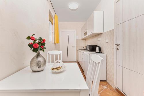a white kitchen with a vase of flowers on a counter at Apartments Vuković in Kotor