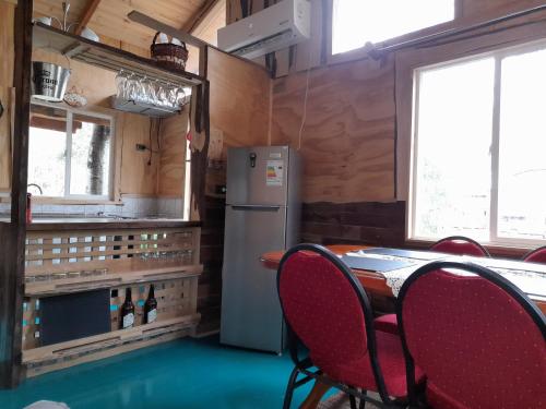 een keuken met een koelkast en een tafel met stoelen bij Cabaña Don Humbert in Riñinahue