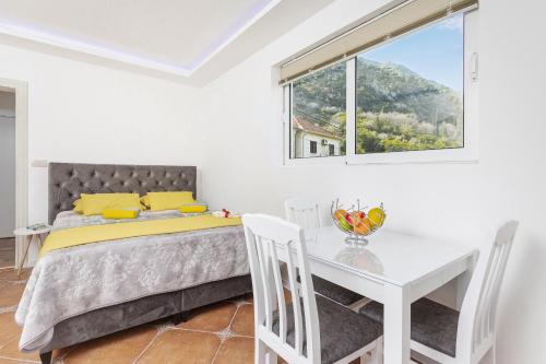 1 dormitorio con cama, mesa y ventana en Apartments Vuković, en Kotor