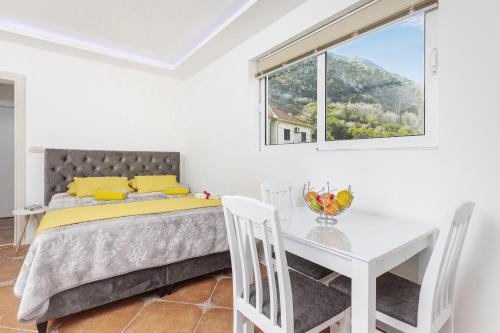 a bedroom with a bed and a table and a window at Apartments Vuković in Kotor