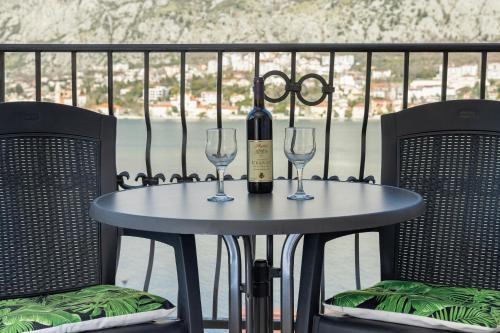 a table with a bottle of wine and two glasses at Apartments Vuković in Kotor