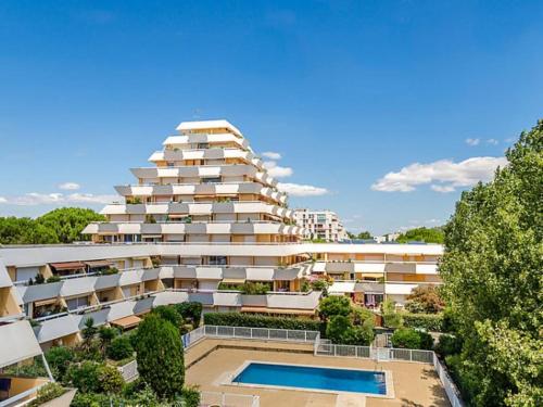 un grand bâtiment avec une piscine devant dans l'établissement DOUKA APPART T2 WIFI CLIM PISCINE en saison - CENTRE PROCHE PLAGE-PORT - La Grande Motte, à La Grande Motte