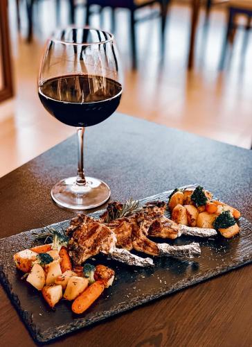 a plate of food and a glass of wine on a table at Meatsa Hotel in Kŭrdzhali