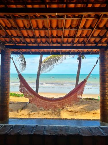 eine Hängematte am Strand mit dem Meer im Hintergrund in der Unterkunft Suíte Pé na Areia - Praia da Peroba - Icapuí in Icapuí