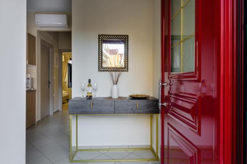 a hallway with a red door and a table with a vase at Nikola's & Joanna's apartments in Argostoli