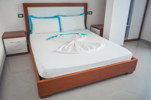 Una cama con sábanas blancas y almohadas azules. en Blue Paradise Hotel, en Orikum
