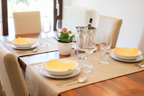 a wooden table with plates and wine glasses on it at VILLA LAURETO - By Apulia Hospitality in Selva di Fasano
