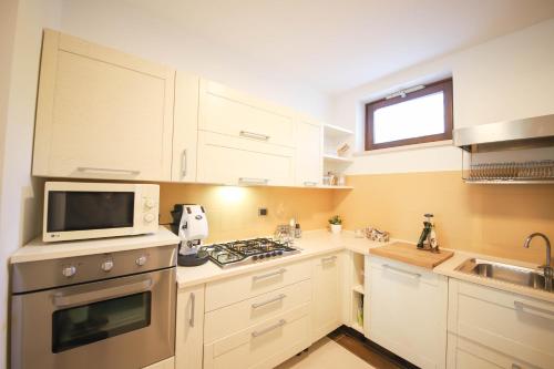 a small kitchen with white cabinets and a microwave at VILLA LAURETO - By Apulia Hospitality in Selva di Fasano
