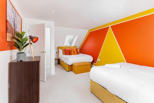 a bedroom with two beds and an orange and yellow headboard at Air Host and Stay - Brand new 3 bedroom house sleeps 8 minutes from LFC and city centre Ref25 in Liverpool