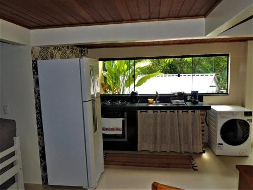 Una cocina con un refrigerador blanco y un microondas. en MICROCASA DE PRAIA, en Angra dos Reis