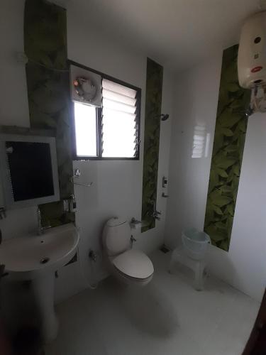 a bathroom with a toilet and a sink and a window at kurinji residency in Ooty
