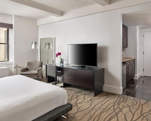 a bedroom with a bed and a desk with a television at AKA Central Park in New York