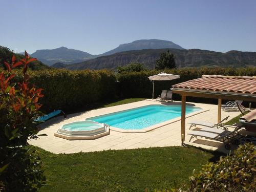 a swimming pool with chairs and an umbrella in a yard at Chambres d'hôtes La Dorgisane in Venterol