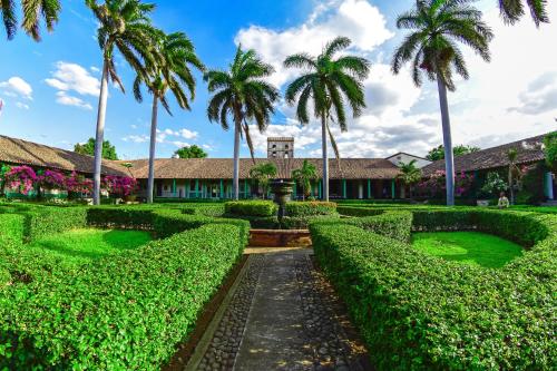 a lush green park with palm trees and palm trees at Hotel El Convento Leon Nicaragua in León
