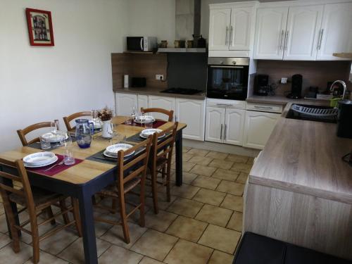 una cocina con mesa y sillas y una cocina con armarios blancos. en Gîte "le pitous", en Cahuzac