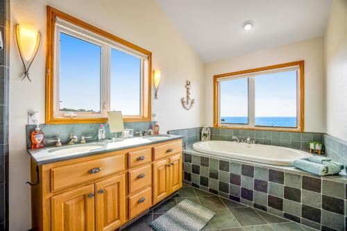 a bathroom with a tub and a sink and two windows at Pelican House in Fort Bragg