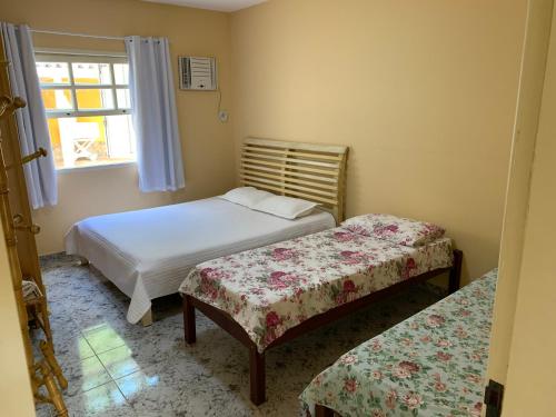 Habitación pequeña con 2 camas y ventana en CASA NO CENTRO DE BUZIOS, en Búzios