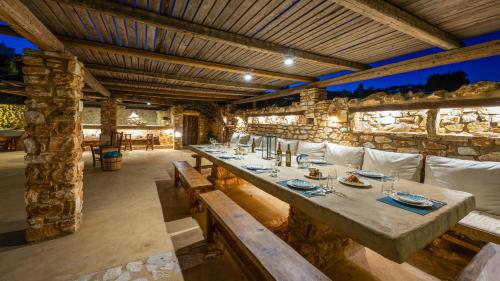a dining room with a long table and a stone wall at BLUE GREENS VILLAS in Kampos Paros