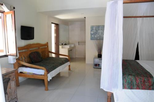 a bedroom with a bed and a television in a room at Frangipani Beach Hotel in Lovina