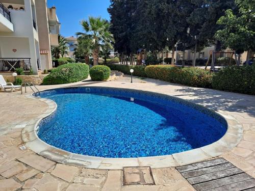 een groot zwembad met blauw water in een tuin bij The well-equipped luxury apartment Paphos Riviera in Paphos City