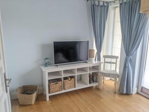 een televisie op een witte stand in een woonkamer bij Apartament Rezydencja Bursztyn in Świnoujście