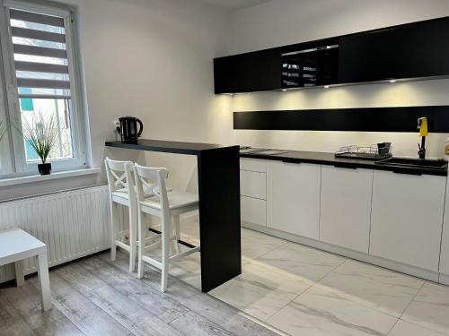 a kitchen with white cabinets and a black counter top at Apartament Stary Zdroj Polanica Resort in Polanica-Zdrój