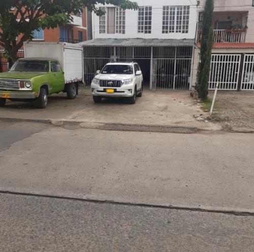 Hospedaje Alférez Real في Jamundí: مركبتين متوقفتين في موقف للسيارات أمام مبنى