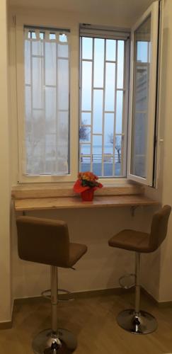 Zimmer mit zwei Stühlen und einer Theke mit zwei Fenstern in der Unterkunft La Casina sul mare in Giovinazzo