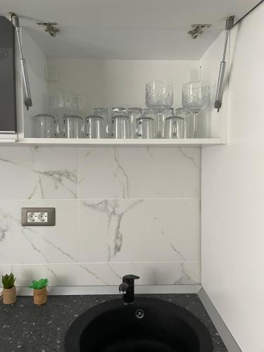 a kitchen with a sink with glasses on a shelf at Studio Philip by Alezzii Nord 10 in Năvodari