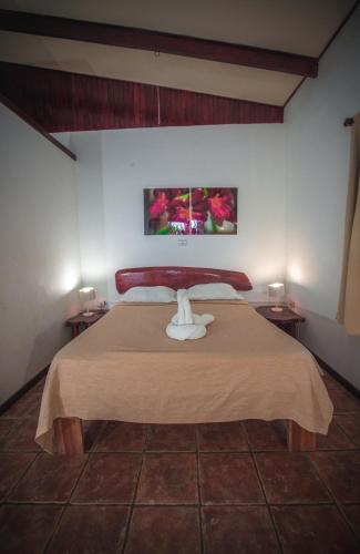 a bedroom with a large bed with two tables at Hotel El Jardin in Montezuma