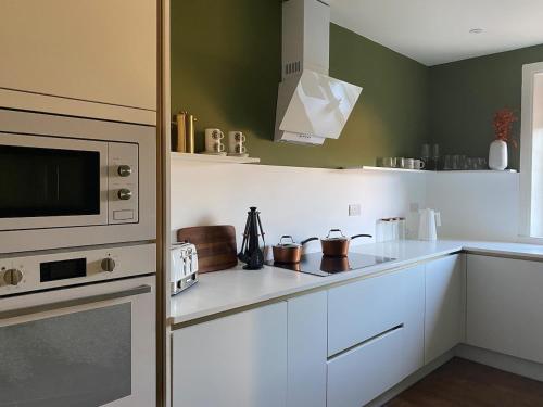 a kitchen with white cabinets and a microwave at Arbroath luxury apartment in MCM style in Arbroath