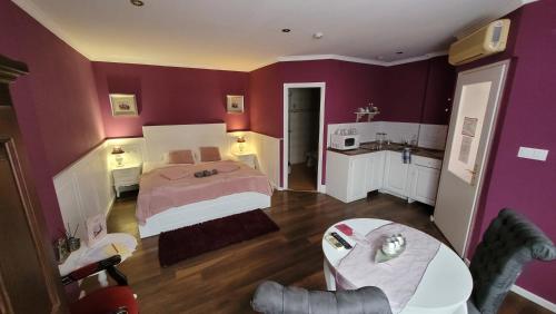 a purple bedroom with a bed and a table at Guest House Romantika Panzio in Gyula