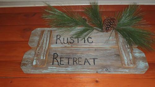 a sign that saysrustic retreat with a pine tree on it at Gas fireplace, firepit, and cedar Adirondack chair in Spencer
