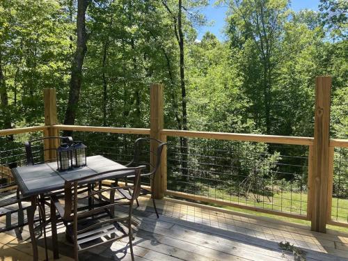 a deck with a table and chairs and a fence at Gas fireplace, firepit, and cedar Adirondack chair in Spencer