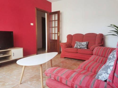 a living room with a red couch and a table at Apto Playa Camelle 1º in Camelle